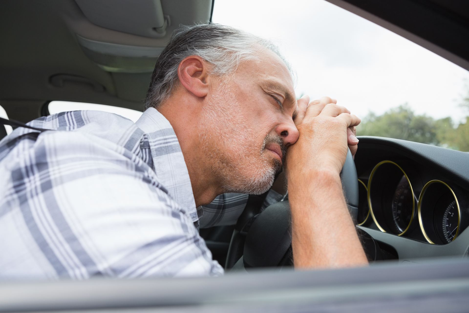 Distressed driver resting his head on the steering wheel after a DWI arrest